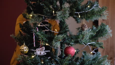 Young-beautiful-woman-setting-up-Christmas-tree-with-ornaments-and-lights-tilting-down-to-up