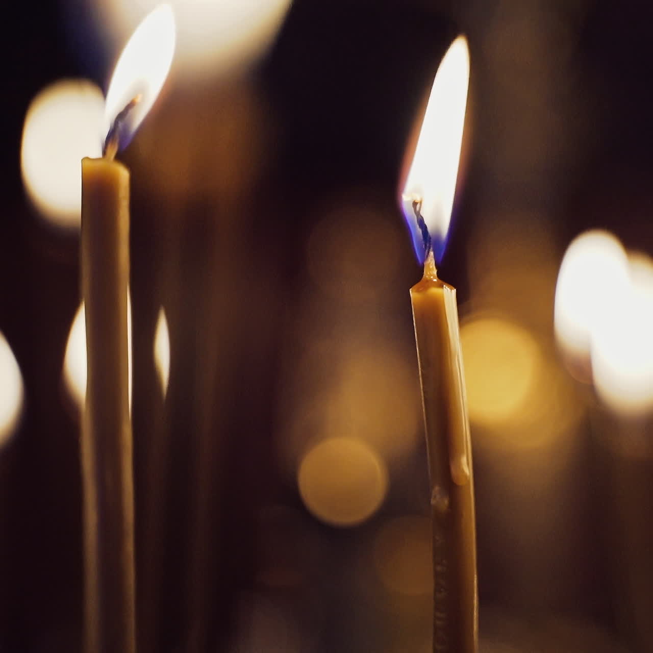 Candles flame brightly in the church. Burning candles on the blurred background with light spots. Close-up