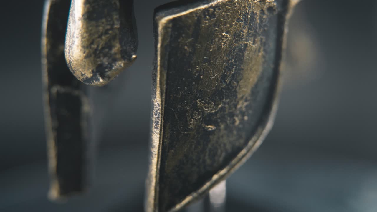 A close up macro detailed slow tilt up shot of a spartan face design, warrior metal bronze helmet, on a 360 rotating stand, studio lighting, 4K smooth movement