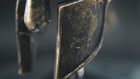 a close up macro detailed slow tilt up shot of a spartan face design, warrior metal bronze helmet, on a 360 rotating stand, studio lighting, 4k smooth movement