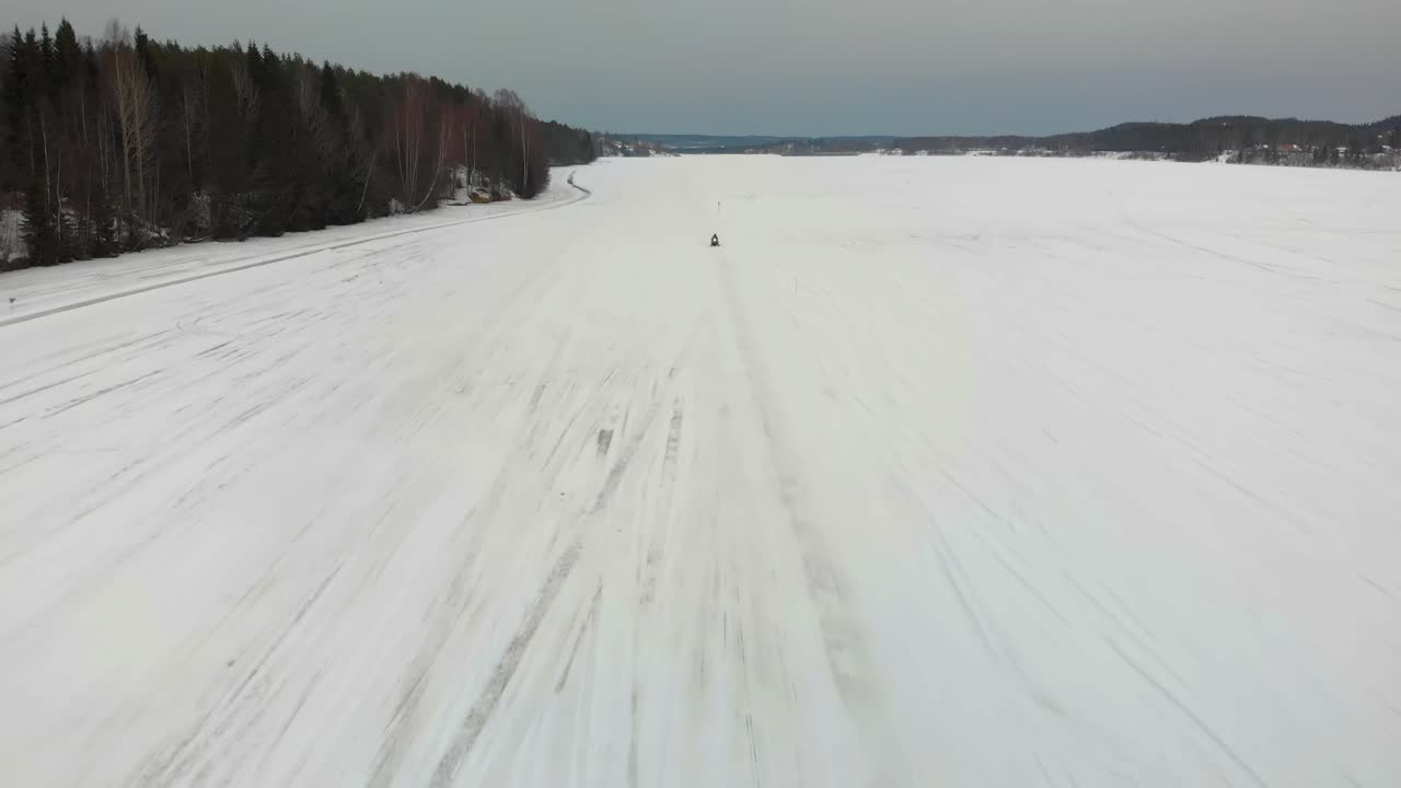 Ripresa aerea di un uomo che guida la sua motoslitta verso la telecamera sull'Indalsälven a Timra, Sundsvall, Svezia