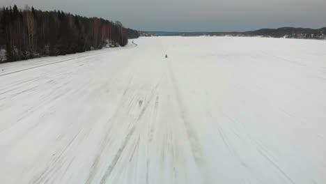 Toma-Aérea-De-Un-Hombre-Conduciendo-Su-Moto-De-Nieve-Hacia-La-Cámara-En-Indalsalven-En-Timra,-Sundsvall,-Suecia