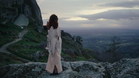 spiritual woman on top of a hill looking at the beautiful sunset horizon long shot