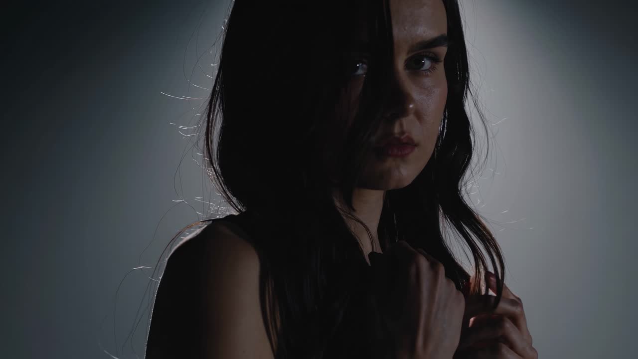 Dramatic video scene with a side angle shot of a woman in a spotlight, creating a mysterious