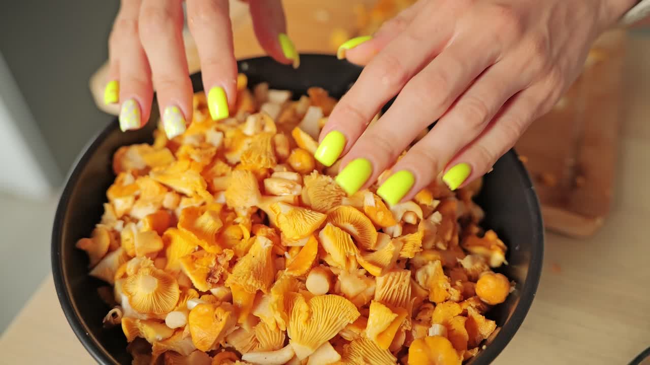 Yellow mushrooms cascade into bowl by hand in slow motion rustic kitchen scene