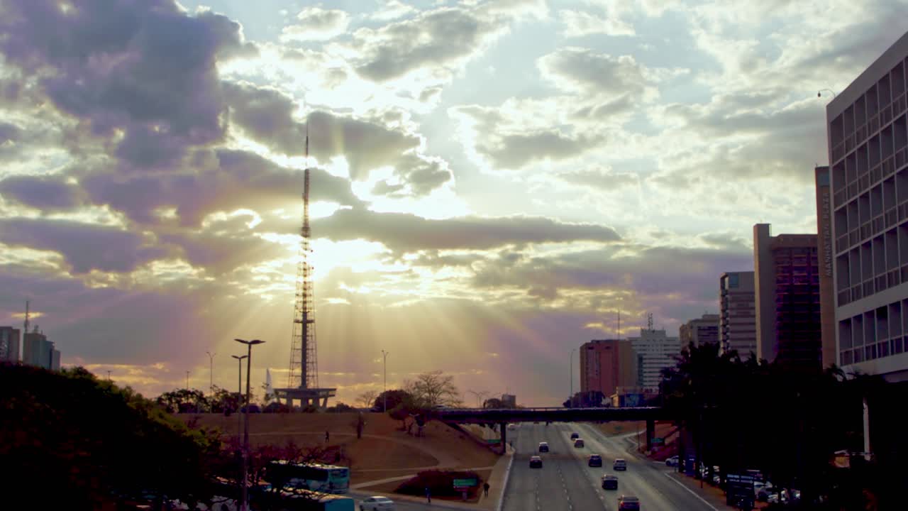 rayos de sol celestiales brillando a través de las nubes al atardecer sobre una carretera en brasilia, brasil