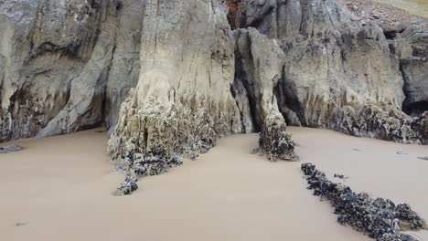 Gruselige-Abstrakte-Meereshöhlen-Am-Sandstrand---4K-Luftdrohnenaufnahme