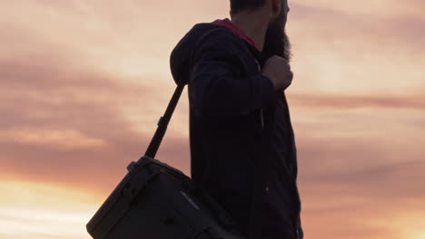 man walking in field sunrise hard case carry field wet grass horizon red sky
