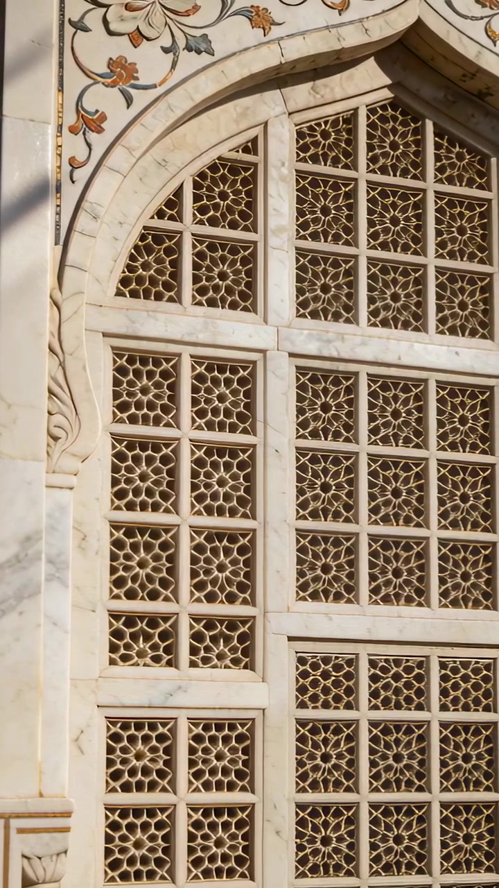 Vertikales Video: Kamera schwenkt von Anfang an, enthüllt ein Jali-Fenster und zeigt Details eines sonnenbeschienenen Bogens.