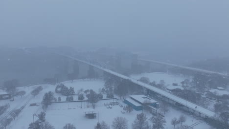 aerial footage flying over coolidge park with the walnut street walking bridge in the background during a snowstorm in chattanooga, tn.