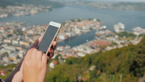 Weibliche-Hände-Mit-Einem-Smartphone-Benutzen-Das-Telefon-Vor-Dem-Hintergrund-Der-Stadt-Bergen-4k-Video