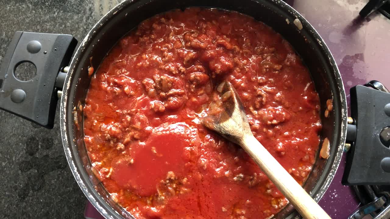 preparando salsa de tomate con carne para la pasta.