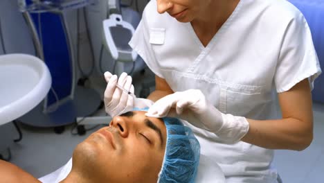 doctor inserting facial injection on male patient forehead