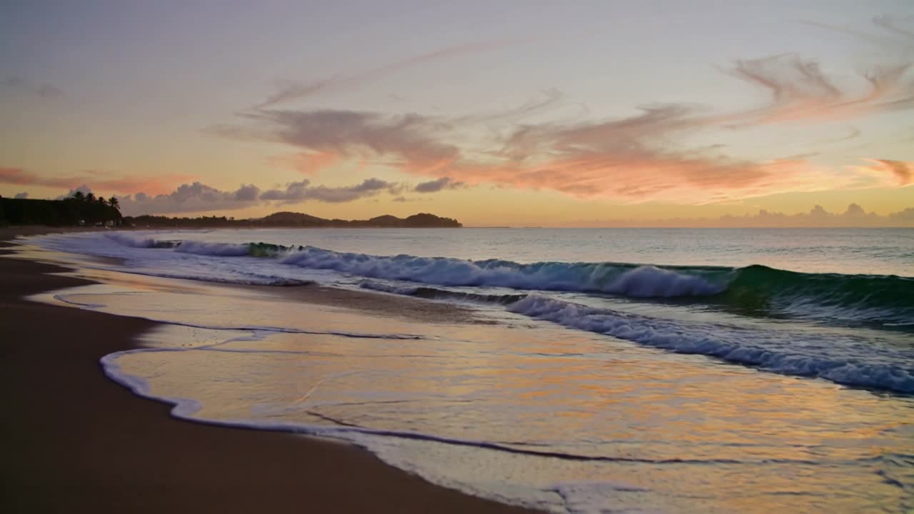Ondas fortes subindo, enrolando e quebrando na costa arenosa ao nascer do sol, deixando a areia molhada.