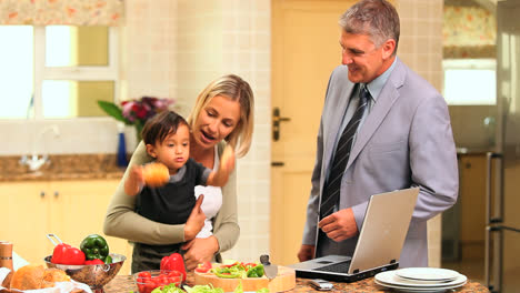 baby holding bread and fidgeting while his parents are laughing