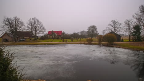 timelapse - sun rising over countryside farm with frozen lake and houses