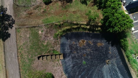 Video-Aéreo-De-La-Planta-De-Tratamiento-De-Aguas-Residuales,-Estanques-De-Retención-Residenciales-Alrededor-Del-área-Verde