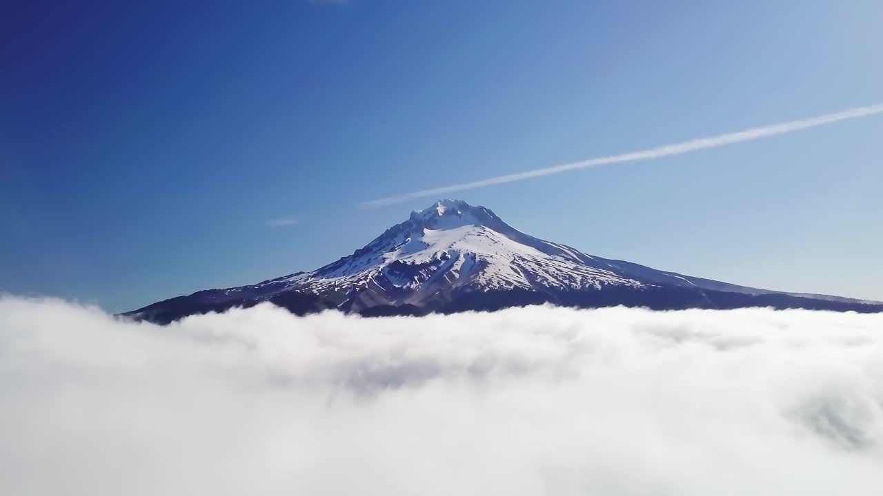 Aerial view of Machhapuchhre in Nepal rising above a sea of clouds, its snow-capped summit gleaming under a bright blue sky, showcasing the Himalayan mountain’s symmetry, beauty, and serenity