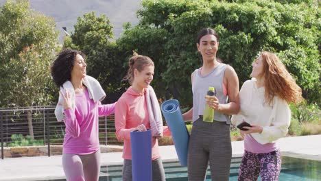 happy group of diverse friends holding yoga mats and taking selfie