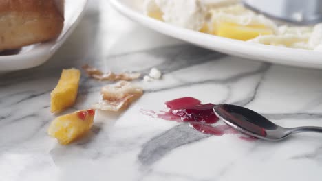 messy marble table with spilled jam and food crumbs