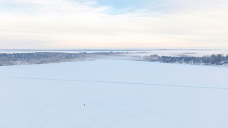 A-breathtaking-wide-shot-panorama-of-nordic-scandinavian-winter-scenery,-forest-and-lakes-covered-by-snow-and-fog