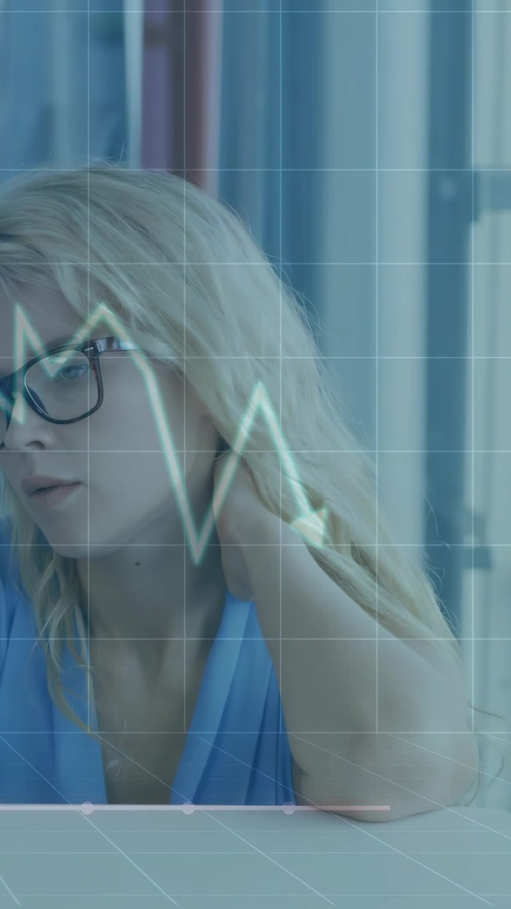 Video verticale: Donna alla scrivania che si tocca il collo, generando una griglia e un grafico della salute pulsante che monitora lo stress.