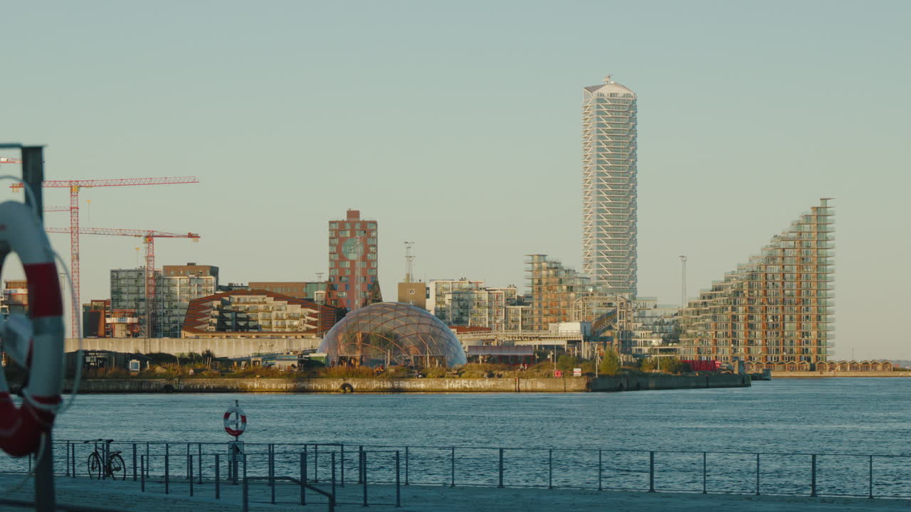 Modern Aarhus waterfront skyline at sunrise. Unique architecture by peaceful waters. Perfect for travel documentaries or urban development promos.