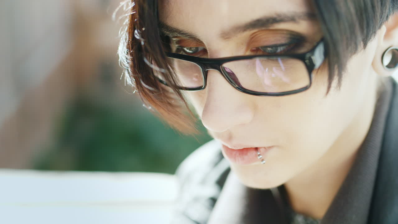 힙스터 안경을 쓴 매력적인 브루네트의 클로즈업이 ph로 그녀의 손을 휴대전화에 타이핑하고 있다