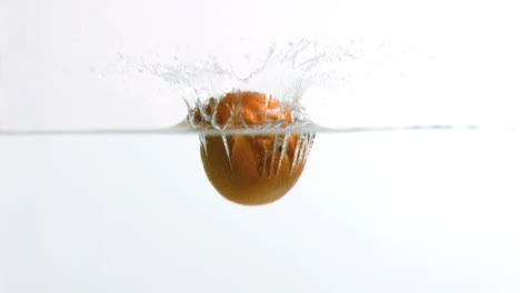 naranja cayendo en el agua en cámara súper lenta