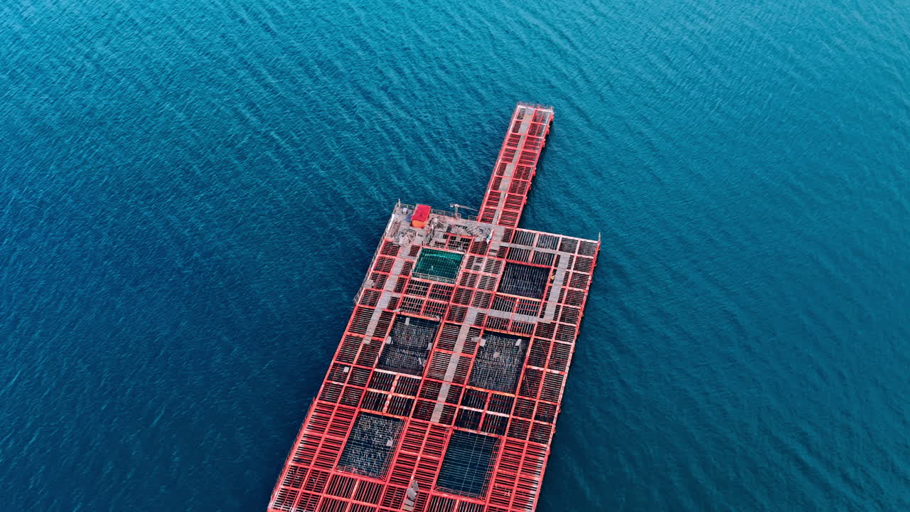 Aerial view of orange metal frames and nets for mussel and fish farming in deep blue water. Top down view of floating aquaculture platform structures