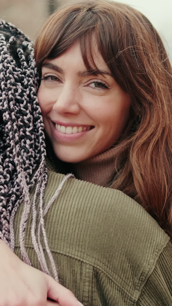 Giovane donna felice che abbraccia un'amica e sorride alla fotocamera