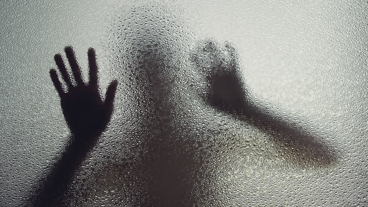 A female silhouette behind the frosted window touches the glass slowly