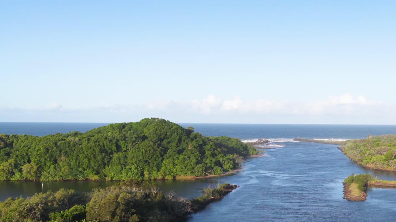 Aerial footage captures a serene river winding through lush green forests under clear blue skies