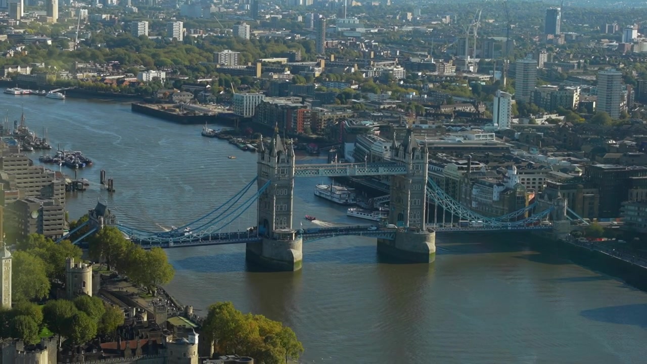 Tower Bridge, der strækker sig over Themsen i London på en klar dag med bybillede i baggrunden.