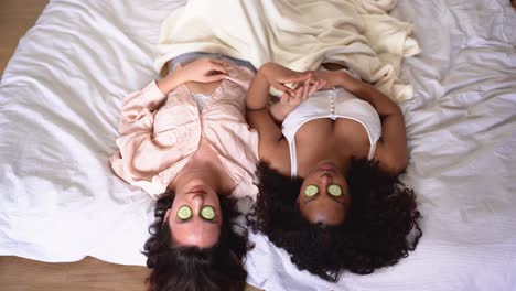 from above of diverse women lying on blanket with cucumber slices on eyes