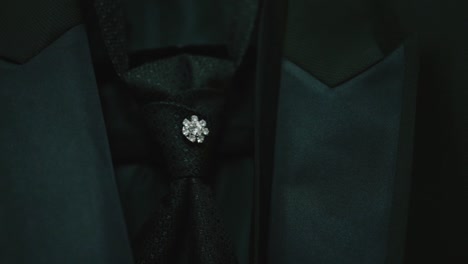 close-up of a dark suit with a sparkling brooch on the tie, emphasizing elegant detail