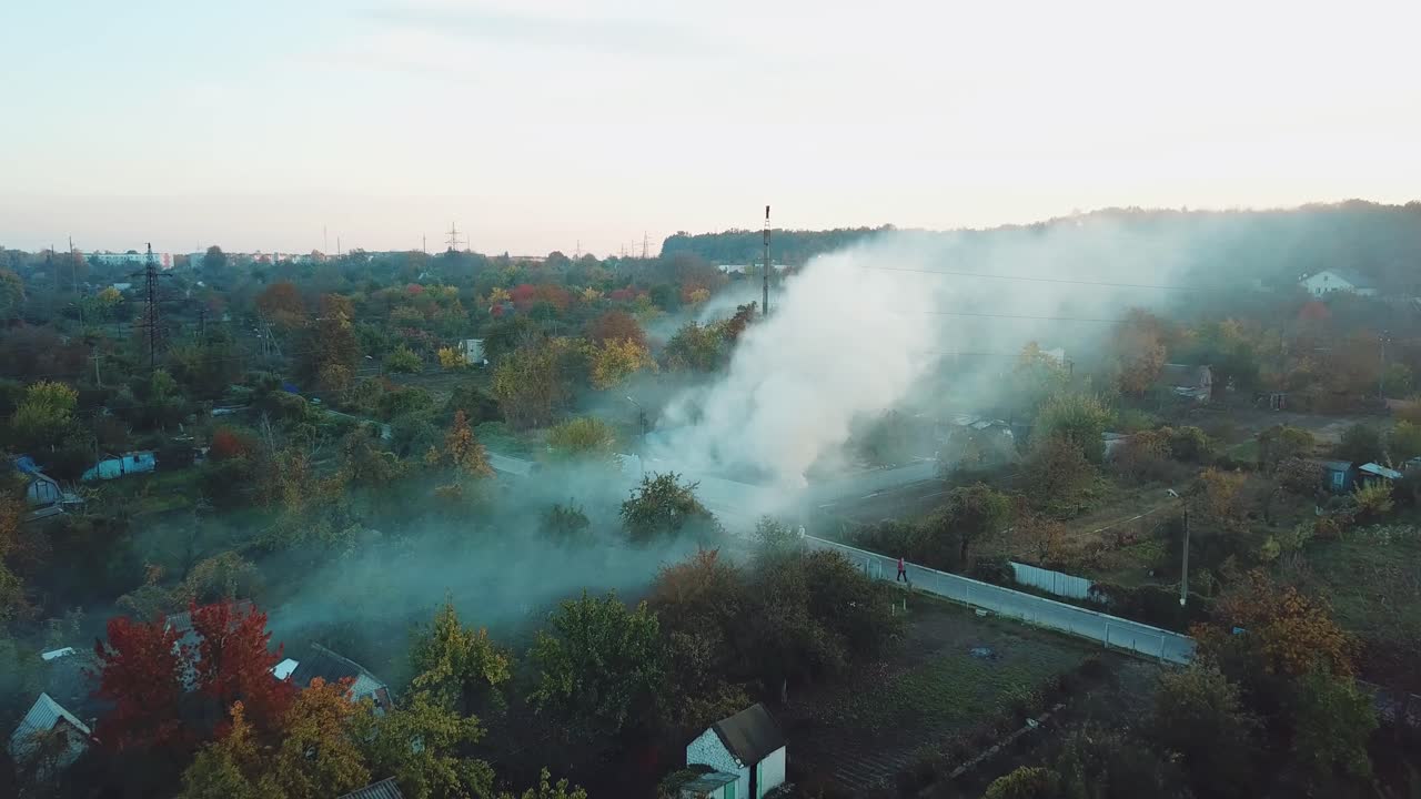 smoke from the fire is filling the space above the private sector of the suburb in the summer. Aerial view
