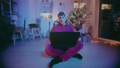 relaxed freelancer closing laptop while sitting at home during christmas