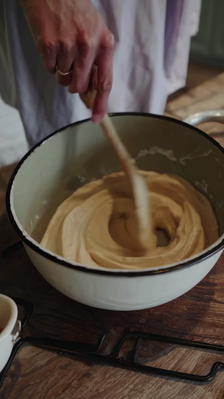 Close-up video shot of a hand mixing batter in a rustic bowl, capturing a cozy, homemade cooking