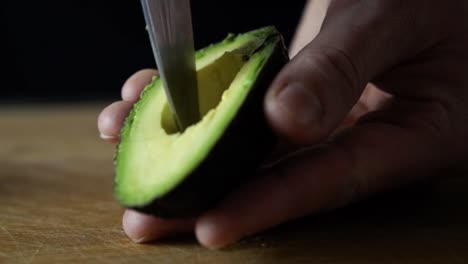 dicing light green avocado inside its skin with tip of sharp chefs knife