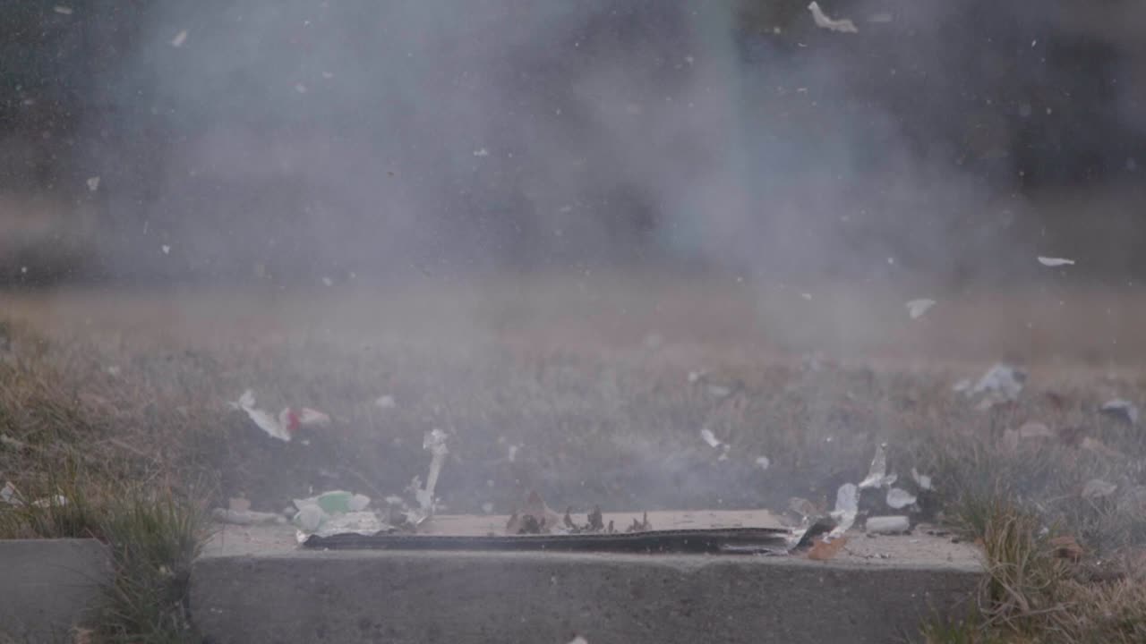 A Christmas ginger bread and graham cracker decoration has a large fire cracker or M 80 lit below it as it burns if finally explodes in slow motion!