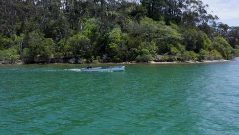 Una-Hermosa-Toma-De-Seguimiento-De-Vista-Total-De-Un-Pequeño-Bote-En-La-Costa-De-Australia,-Con-Un-Día-Soleado,-árboles,-Mar-Y-Luz-Del-Día