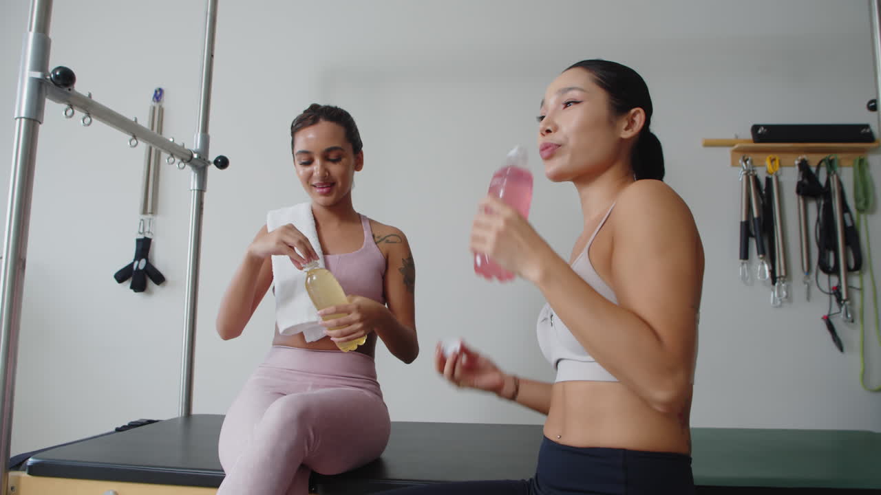 Two Asian Sportswomen Having Healthy Drinks after Intensive Training