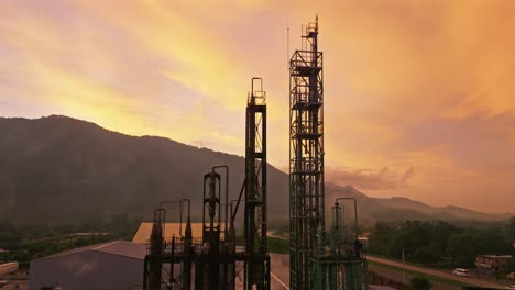 Aerial-view-showing-building-of-factory-in-front-of-mountain-silhouette-at-golden-sunrise