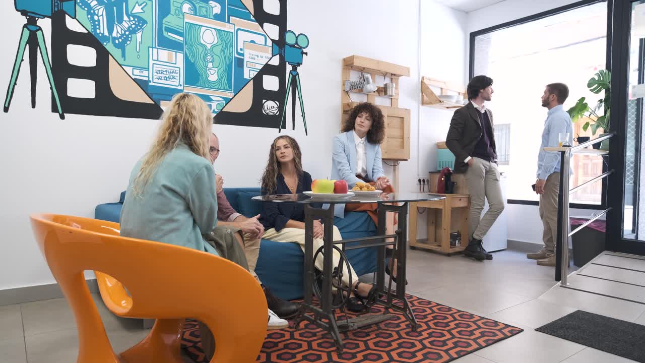Creative business colleagues conversing during break in office canteen