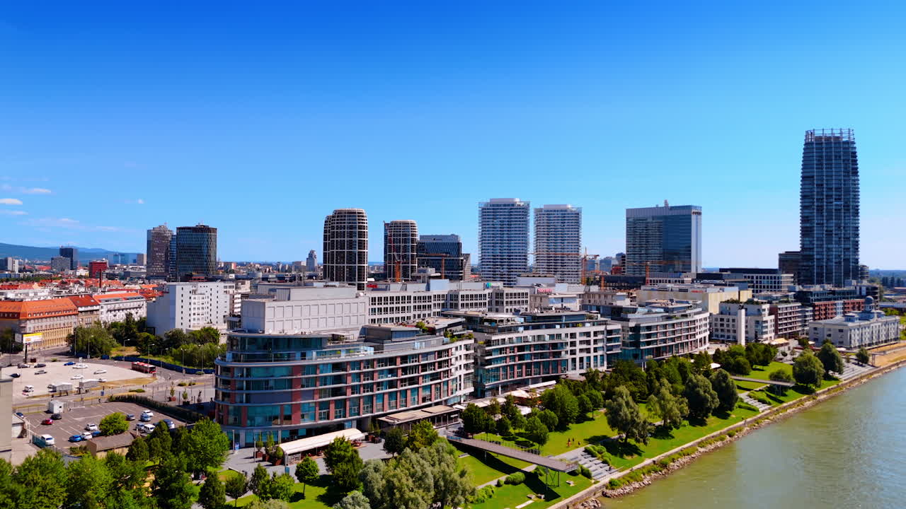 Bratislava skyline has river views. Bratislava showcases a vibrant skyline along the Danube River on a clear, sunny day, highlighting modern architecture