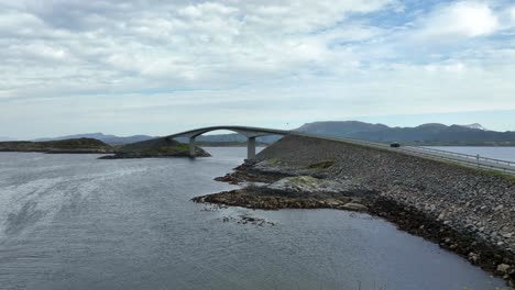 famous storseisundet bridge along atlantic ocean road in norway - forward moving aerial with foreground bushes before ascending