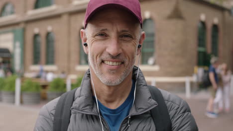 retrato de un hombre caucásico atractivo maduro sonriendo optimista usando auriculares escuchando música disfrutando de vacaciones de viaje