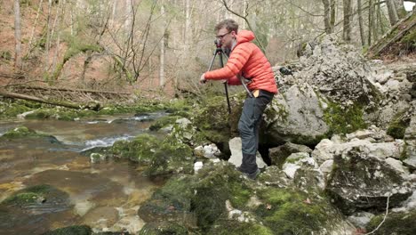 Man-setting-up-a-tripod-next-to-a-river