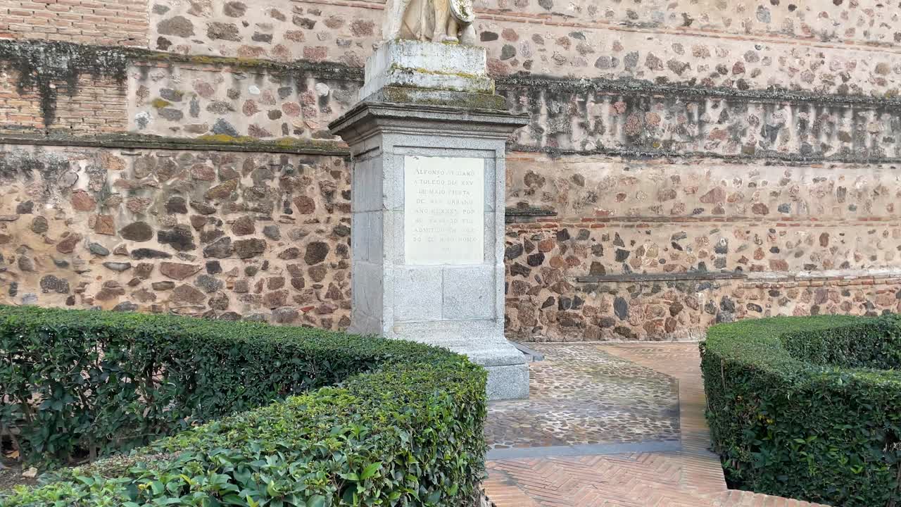 Filming in a park in Toledo of the statue of Alfonso VI with a perfect posture standing on a pedestal with an inscription. We see the hedges and the wall of Toledo in the background.